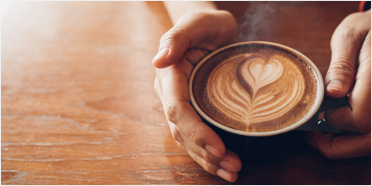 湯気が立ち上るラテアートされたコーヒーカップ