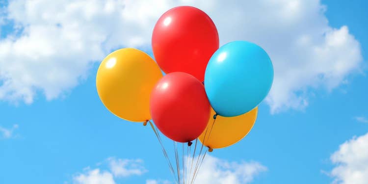明るい青空と雲を背景にした、赤・黄・青の風船