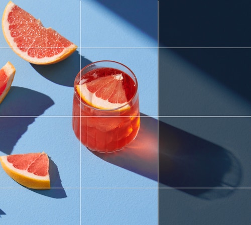 ピンクのカクテルとグレープフルーツのスライスを写した写真。カクテルグラスが落とす影の全体像が見えるように拡張されている