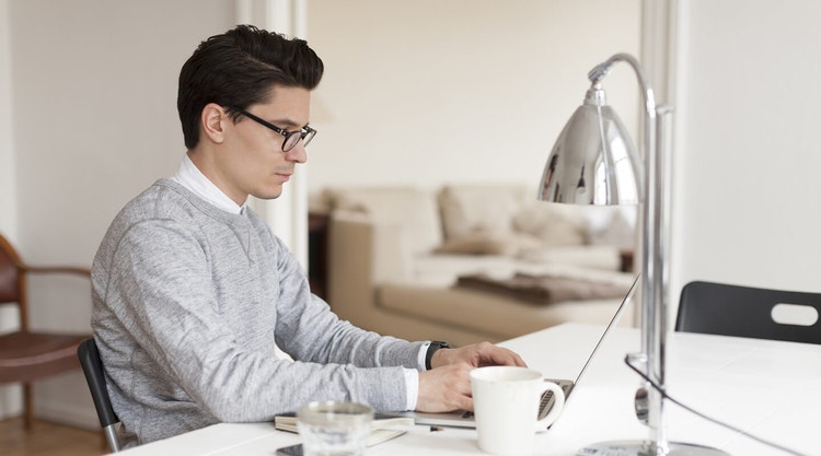 A person sitting at their kitchen counter using their laptop to add a digital certificate to a document