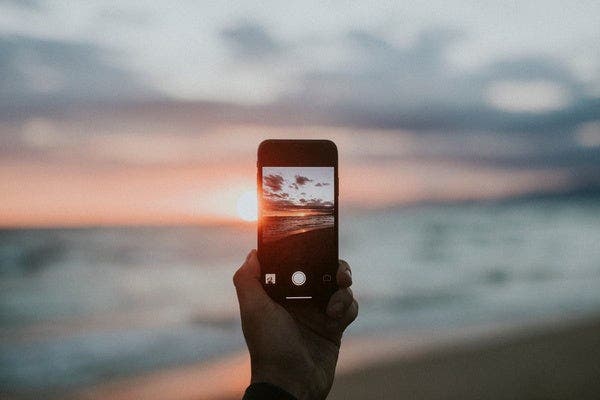 해변 일몰 사진을 아이폰으로 촬영하는 모습