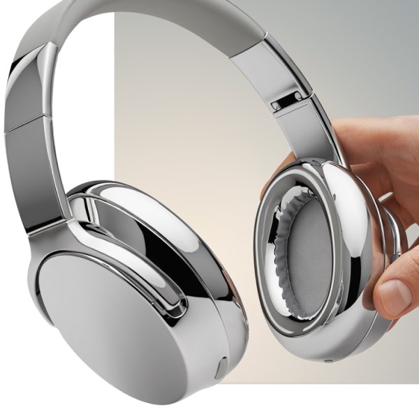 Eine Hand hält ein Paar elegante silberne Over-Ear-Kopfhörer vor einem neutralen Hintergrund.
