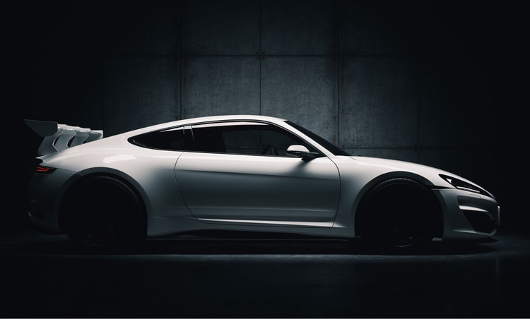 Elegants balts sporta automobilis vāji apgaismotā rūpnieciskā vidē pie tumšas, fakturētas sienas.