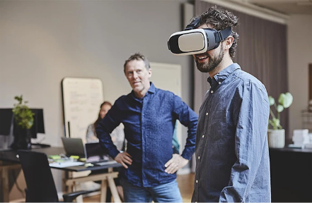 Vīrietis lieto papildinātās realitātes ierīci, kamēr citi vēro