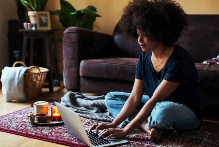 Mujer trabajando en su Mac en el suelo de su sala