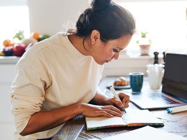 Mujer dibujando en un libro sobre la mesa