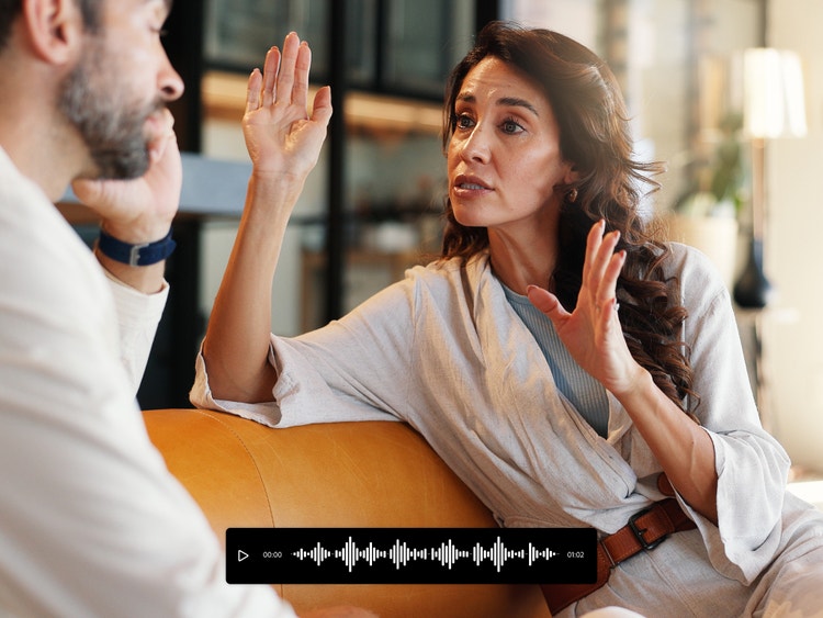 Dua orang sedang berbual di atas sofa dengan tindihan bar audio alih suara AI.