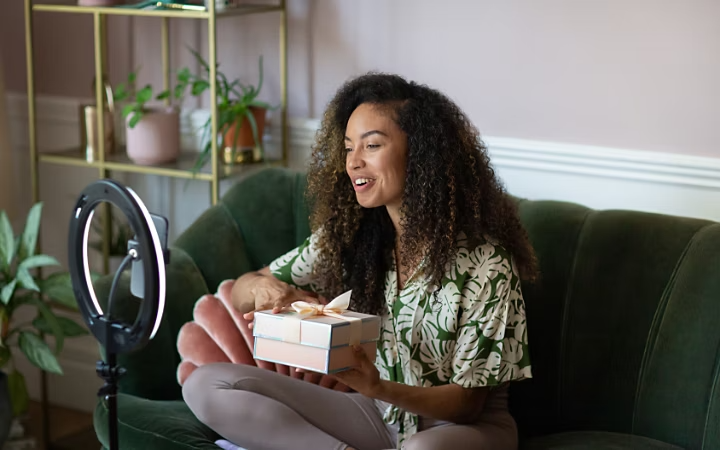 A photo of a person recording a selfie video on the couch in their sitting room.