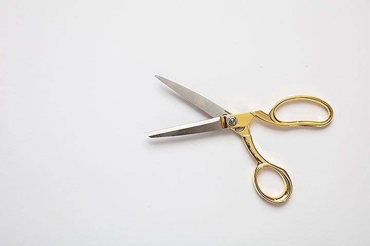 Gold scissors open on a white background.