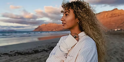 A portrait photo of a person standing on the beach and staring out into the ocean