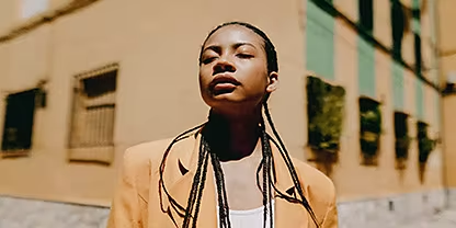 A photo of a person posing in front a building