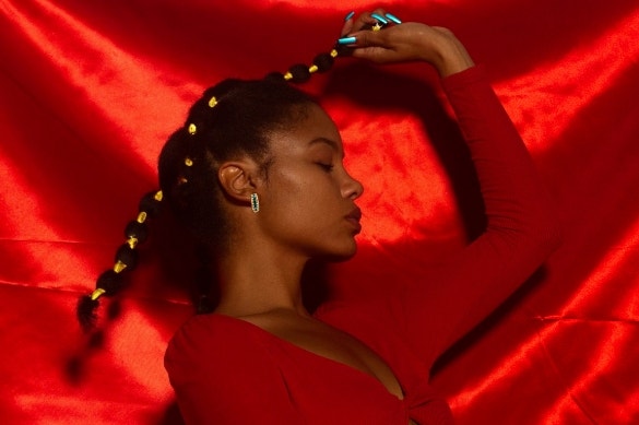 woman holding her hair in front of red background
