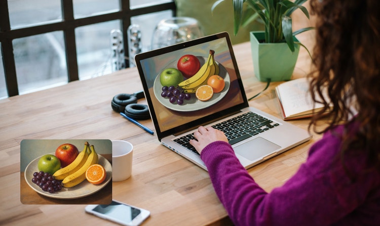 A woman at a computer creating a still life image of fruit. UI in the lower left corner shows the same image of fruit.