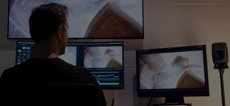 A man editing video in front of multiple monitors