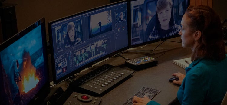 A woman editing video using multiple monitors