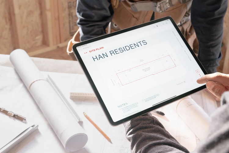 Duas pessoas num estaleiro a analisar planos num tablet, a aprender a comprimir um JPEG.