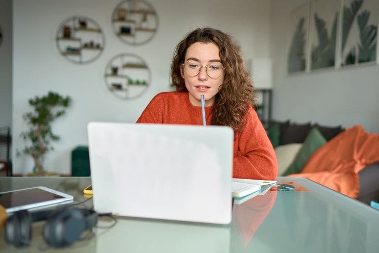 Uma mulher numa sala de estar a utilizar um portátil para converter uma apresentação do PowerPoint num documento do Word.