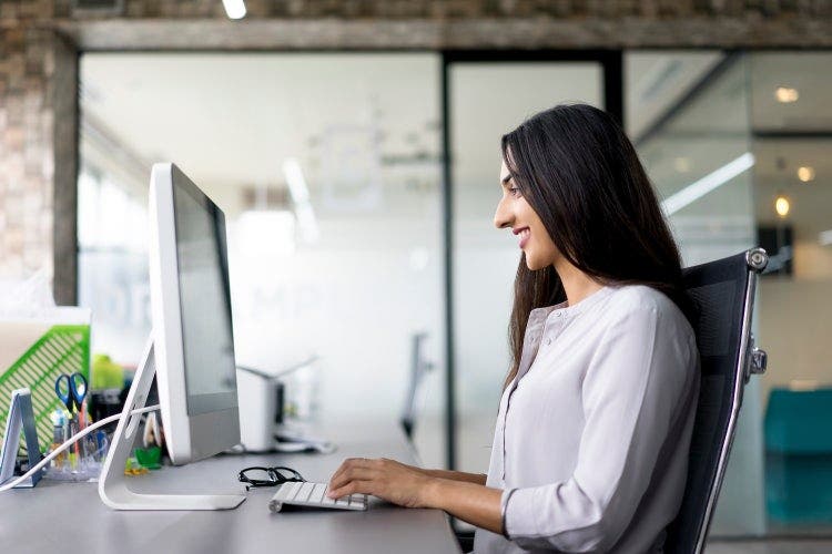Mulher sentada à secretária utiliza o computador para transformar um PDF em Google Slides para uma apresentação.