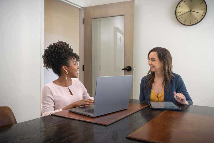 Duas mulheres num escritório a conversar sobre como converter ficheiros de impressão em PDFs.