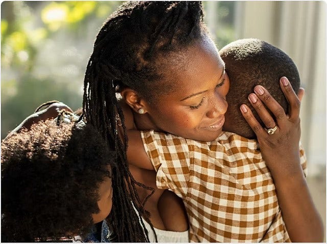 A woman hugging two children