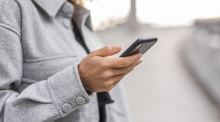 O persoană care ține un telefon mobil în mână și aplică o semnătură S pe un document digital