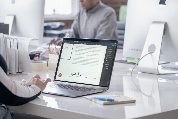 A photo of an employee digitally signing a noncompete agreement on a laptop using the Adobe Acrobat Fill & Sign tool.