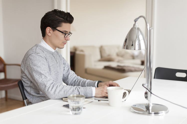 A person sitting at their kitchen counter using their laptop to add a digital certificate to a document