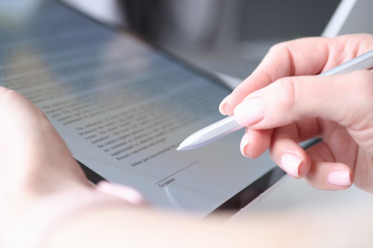 A woman uses a stylus to sign a fillable PDF on a tablet.