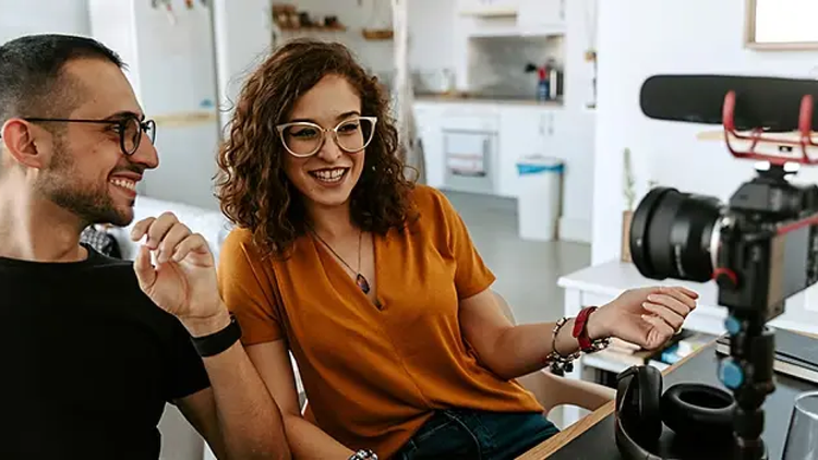 คนสองคนอยู่หน้ากล้องวิดีโอในสภาพแวดล้อมที่เป็นสำนักงานที่บ้าน