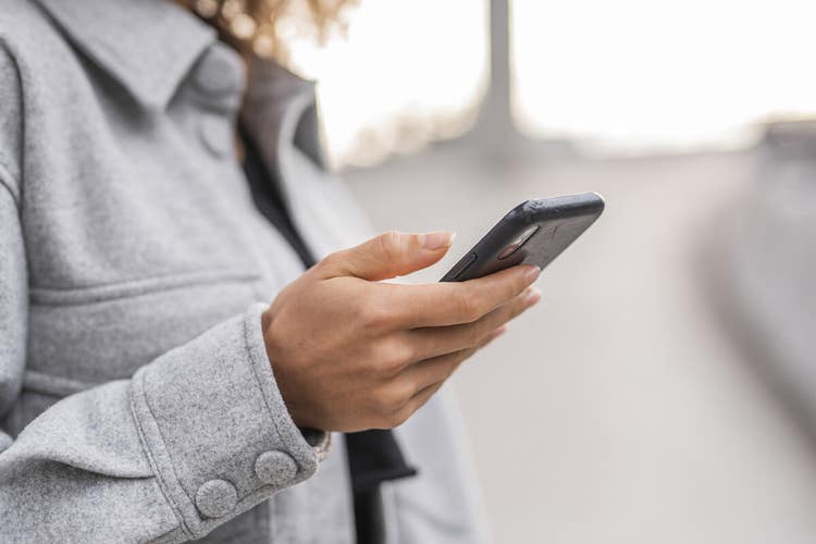 Elinde cep telefonu tutarken dijital bir belgeye s-imza atan bir kişi