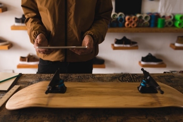 A person putting together an order form using Adobe Acrobat while also working on a new skateboard deck