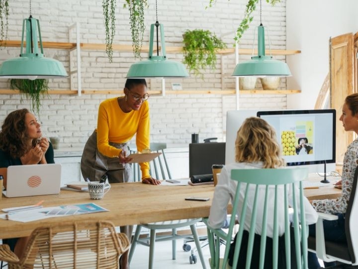 Three coworkers in a modern-looking office go review and discuss a business proposal that has been constructed using Adobe Acrobat.