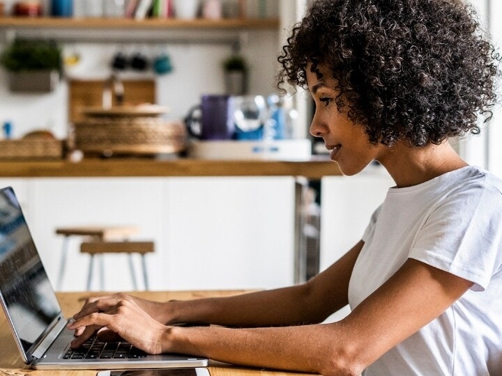 A person sitting at a kitchen island and working on their laptop