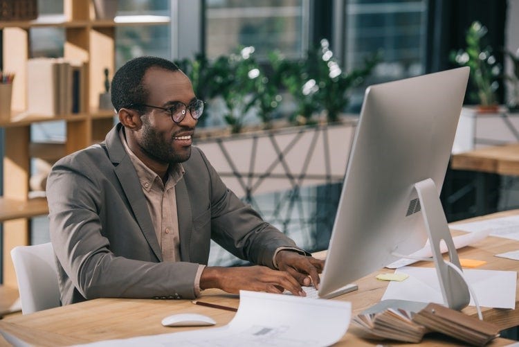 A man sitting in front of a desktop computer to convert PDFs to CSV files with an online converter.