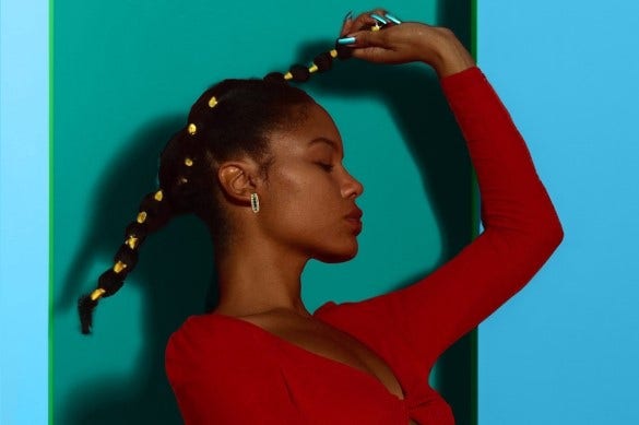 Model holding up braided hair against blue and green AI-generated background for product photography