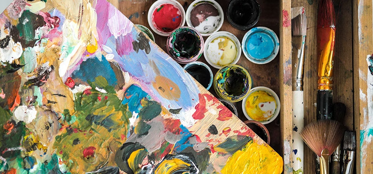 Open paint cans and splotches of multicoloured paint on the table