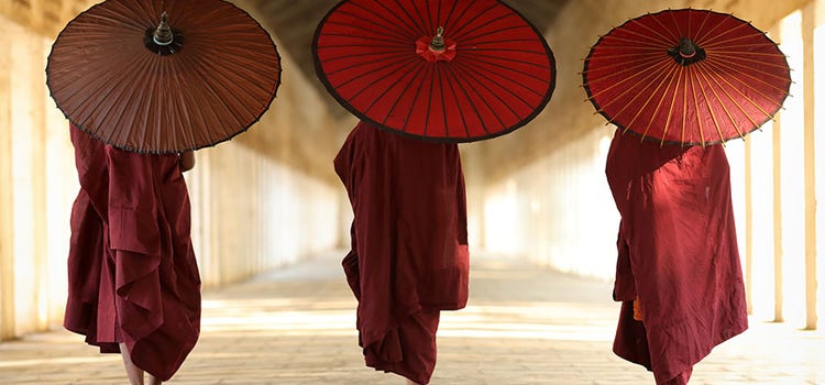 Photo of three figures walking with umbrellas