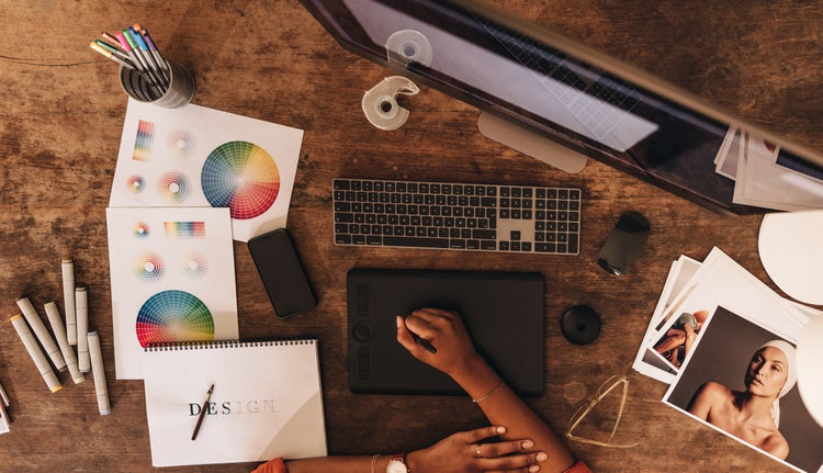 Overhead photo of a desk with a computer, images and colour wheels