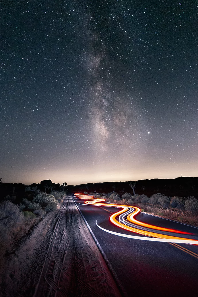 Light trails hovering over a desert carriageway from a car driving through