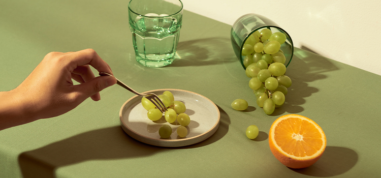 Grapes, a cut orange and glass of water on a tabletop as an example of composition in photography