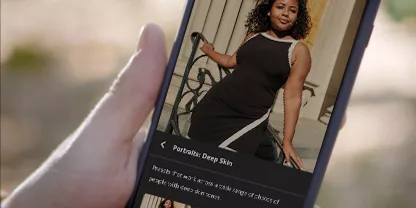 Hand holding a phone showing an image of a woman in a black and white dress in the Lightroom Mobile interface.
