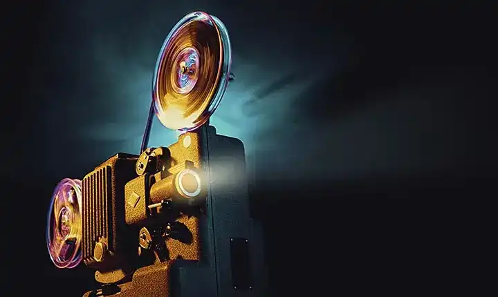 Vintage film projector reels illuminated in a dark room, representing the history of animation